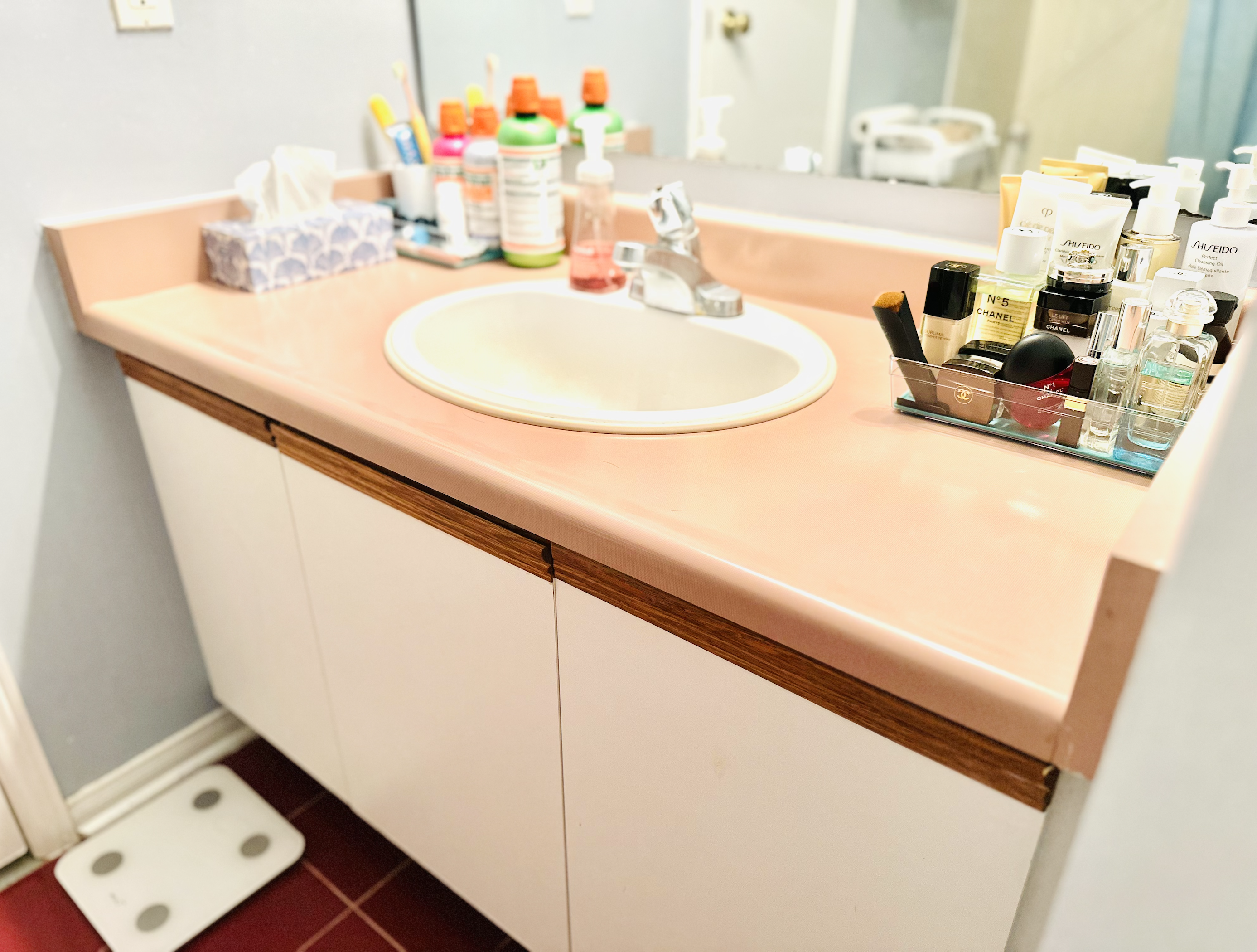 Wide view of a bathroom sink area with a wooden cabinet underneath