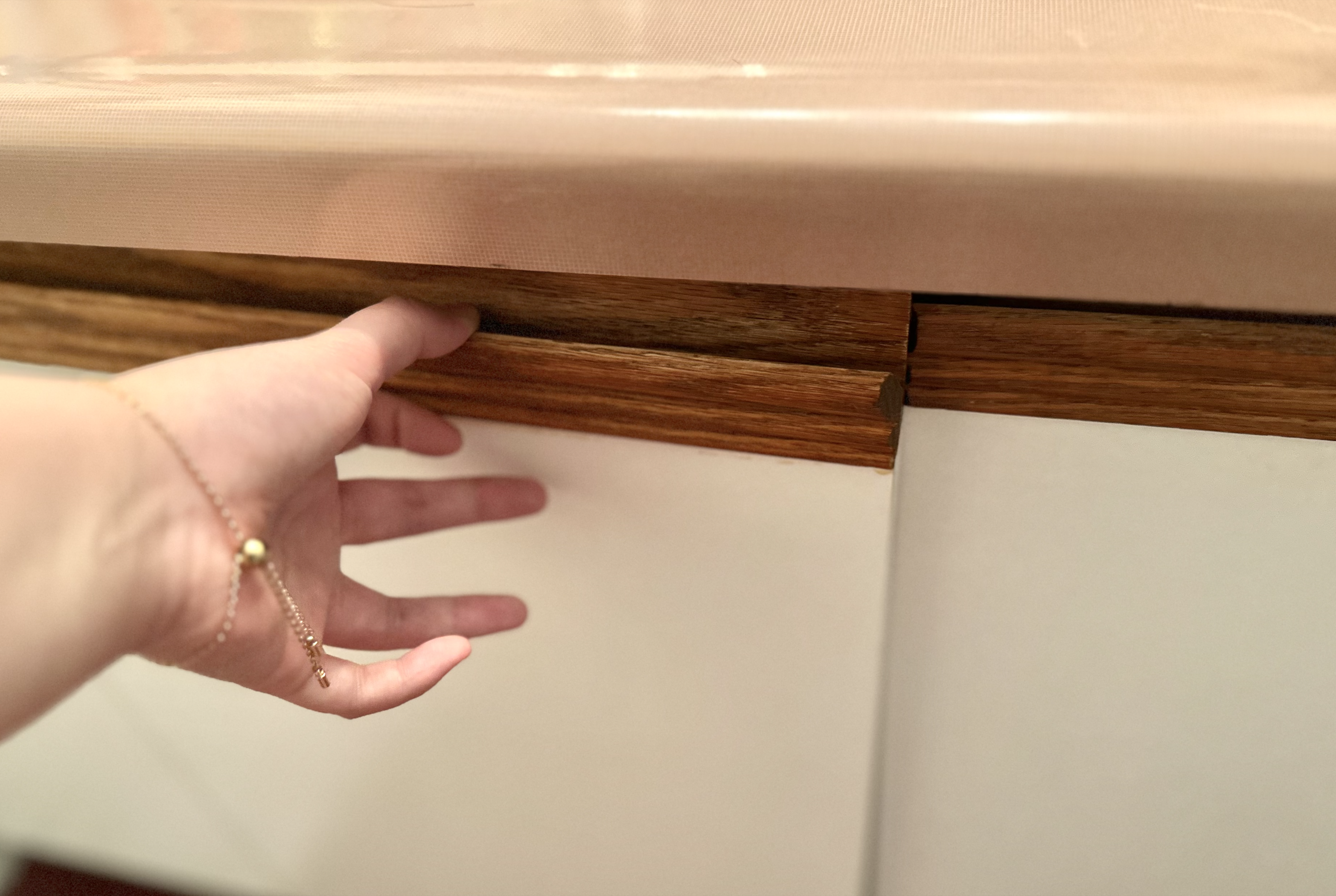 Pushing the cabinet door normally, where it does not fully close due to the age of the wood